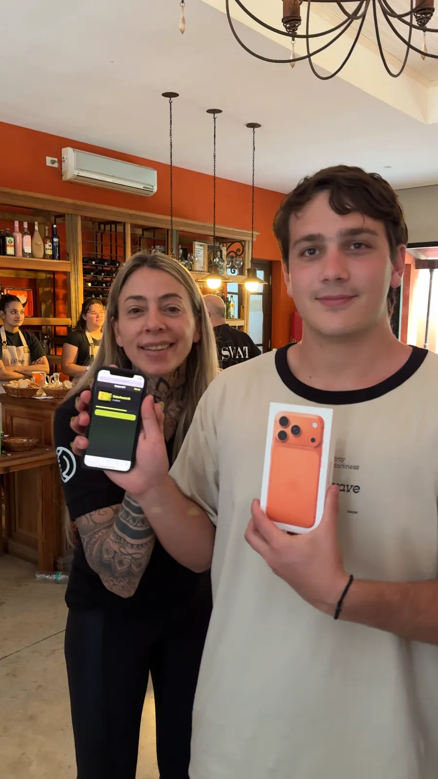 Lucas sostiene la caja del iPhone 17 Pro naranja mientras la anfitriona de Eolax muestra el premio acreditado en pantalla.
