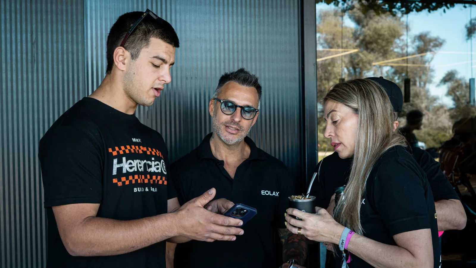 Un asistente muestra en su teléfono el ticket del oxeo a dos integrantes del equipo de Eolax.