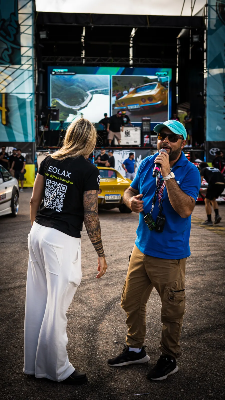 La anfitriona de Eolax, con el QR en la espalda de su remera, habla junto al locutor del evento en la pista.